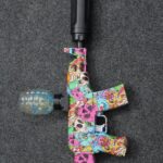 Graffiti AK47 Gel Blaster with colorful skull design, black suppressor, and grenade hopper next to its original box.