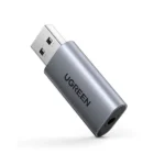 UGREEN 80864 desktop multi-port USB external stereo sound card adapter in a dark matte finish featuring a central mechanical volume adjustment knob, separate microphone and audio mute buttons with LED indicators, three 3.5mm auxiliary jacks, and a 1-meter connecting cable