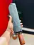 Premium 12-Rib Automatic Open/Close Wooden Handle Umbrella packed inside its compact 3 fold chevron patterned gray protective fabric sleeve while being held upright showcasing its polished brown wooden color handle base and gold accent trim ring