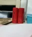 Cylindrical 18650 3.7V rechargeable lithium ion battery cell showing its protective red insulation casing wrapping around a steel button top terminal showing its 3000mAh capacity label print