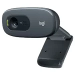 Logitech C270 HD webcam highlighting its compact dark gray oval casing front camera lens aperture green LED status indicator light bar and flexible monitor display mount stand clip