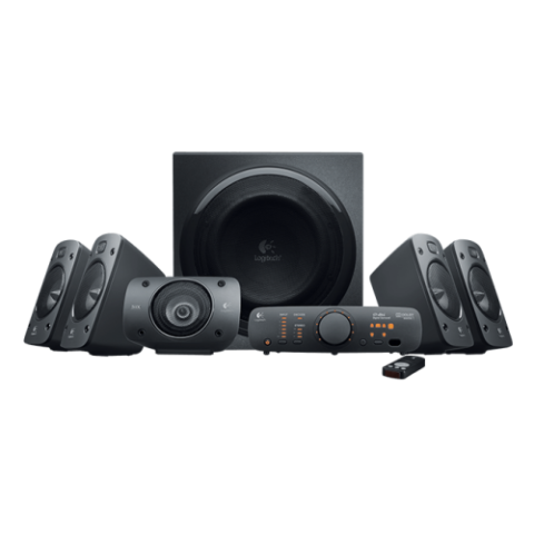 Logitech Z906 5.1 surround sound theater speaker system displaying its four angled satellite speakers, horizontal center channel unit, large side firing wooden subwoofer box, sleek desktop control console module, and slim wireless remote lines